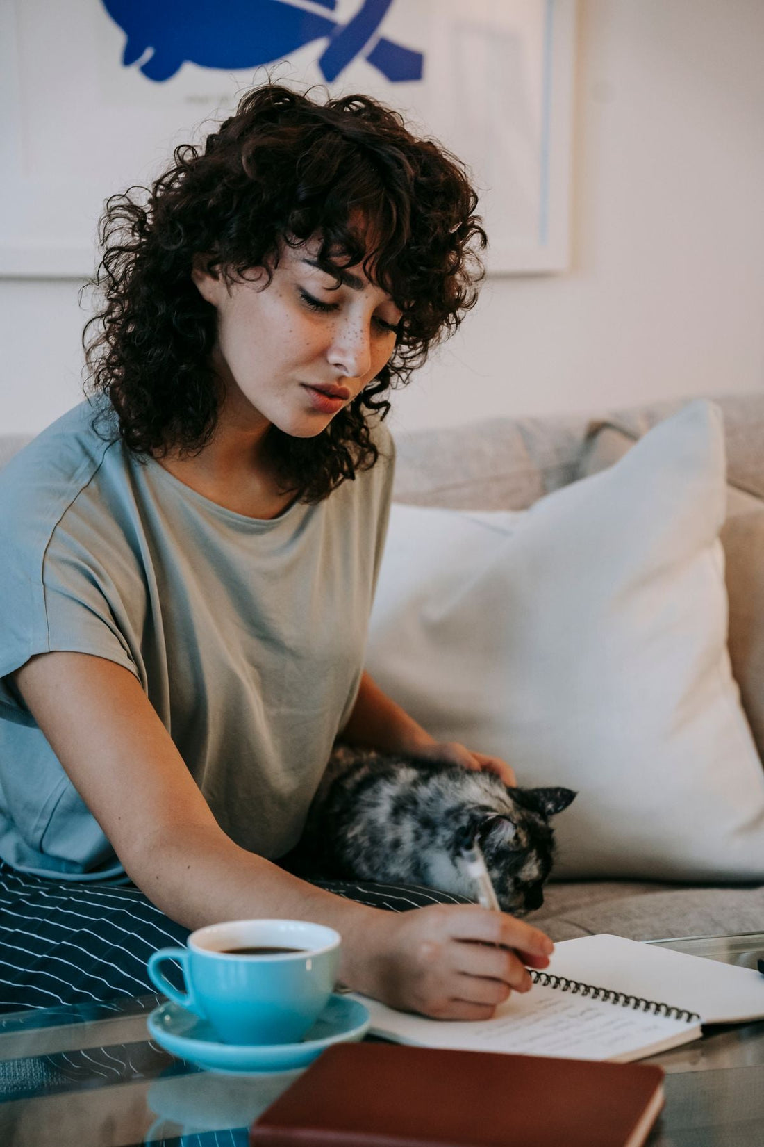 猫をなでながらノートを書く女性